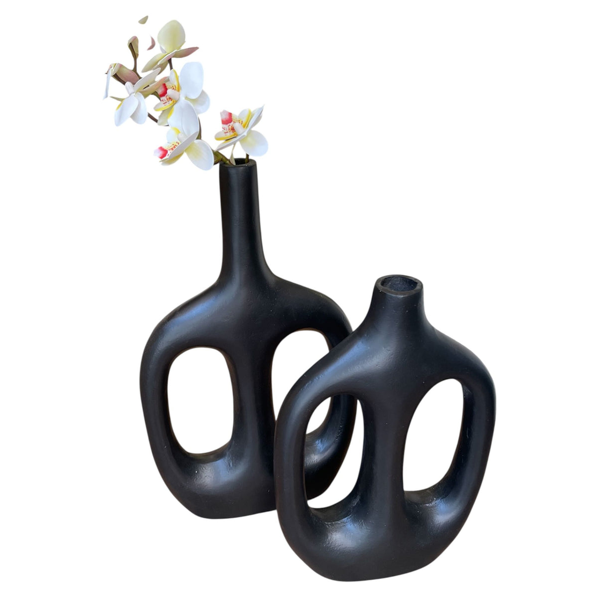 Two black ceramic vases with a single white flower on a white background