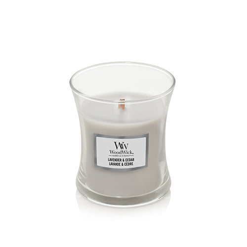 WoodWick Lavender & Cedar scented candle in a clear glass jar with a white wax fill and a white label on the front, set against a plain white background.