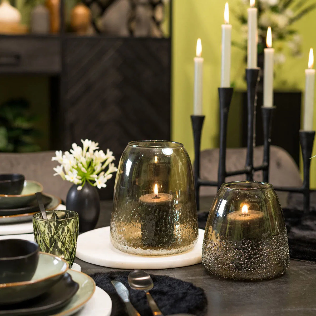 A beige glass candle holder with a frosted pattern, containing a candle, with a clear glass top.