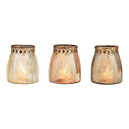 Three cylindrical brown glass windlights with geometric patterns, lit from the inside, showcasing a warm glow.