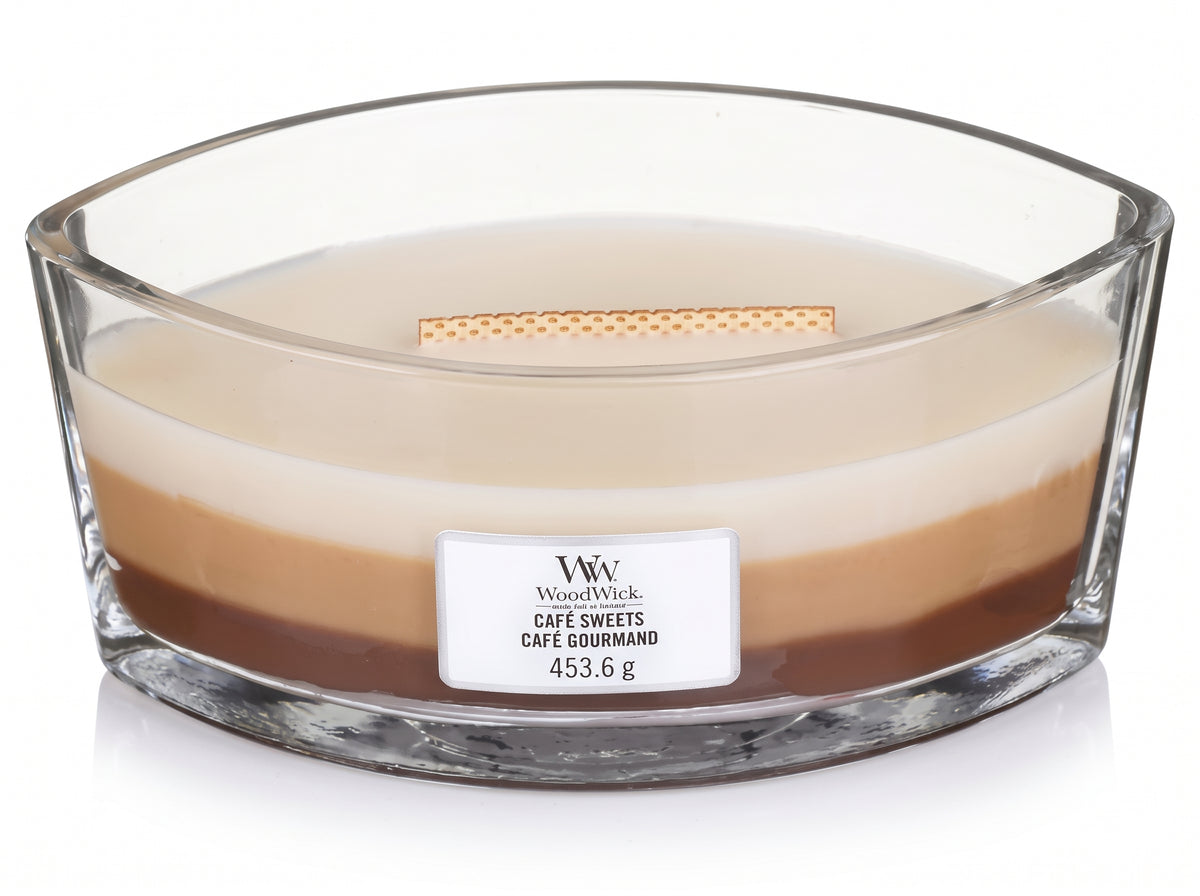 WoodWick Café Sweets Trilogy candle in a clear glass jar with an open lid.