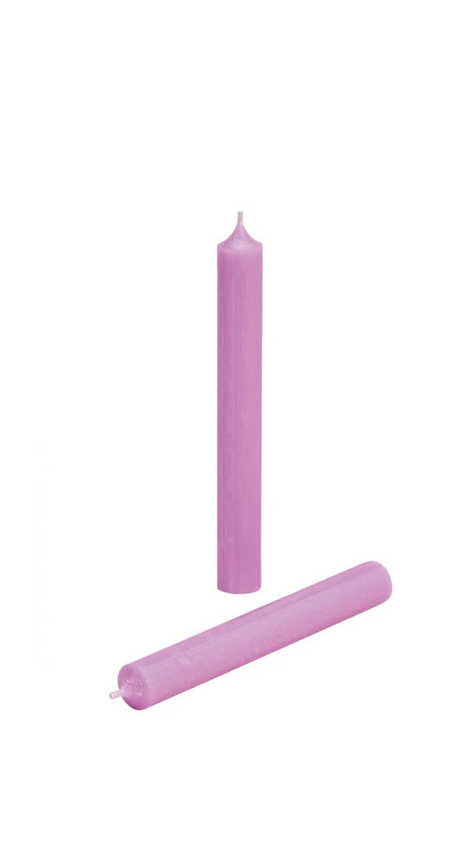 Two pastel violet candles on a white background, one standing upright and one lying horizontally.