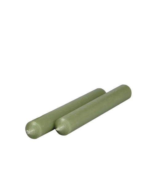 Two sage green colored candles placed one after the other against a white background.