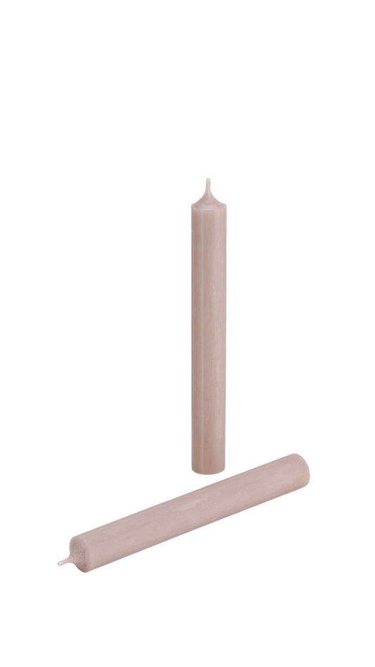 Two cylindrical candles in a taupe/pink color on a light background.