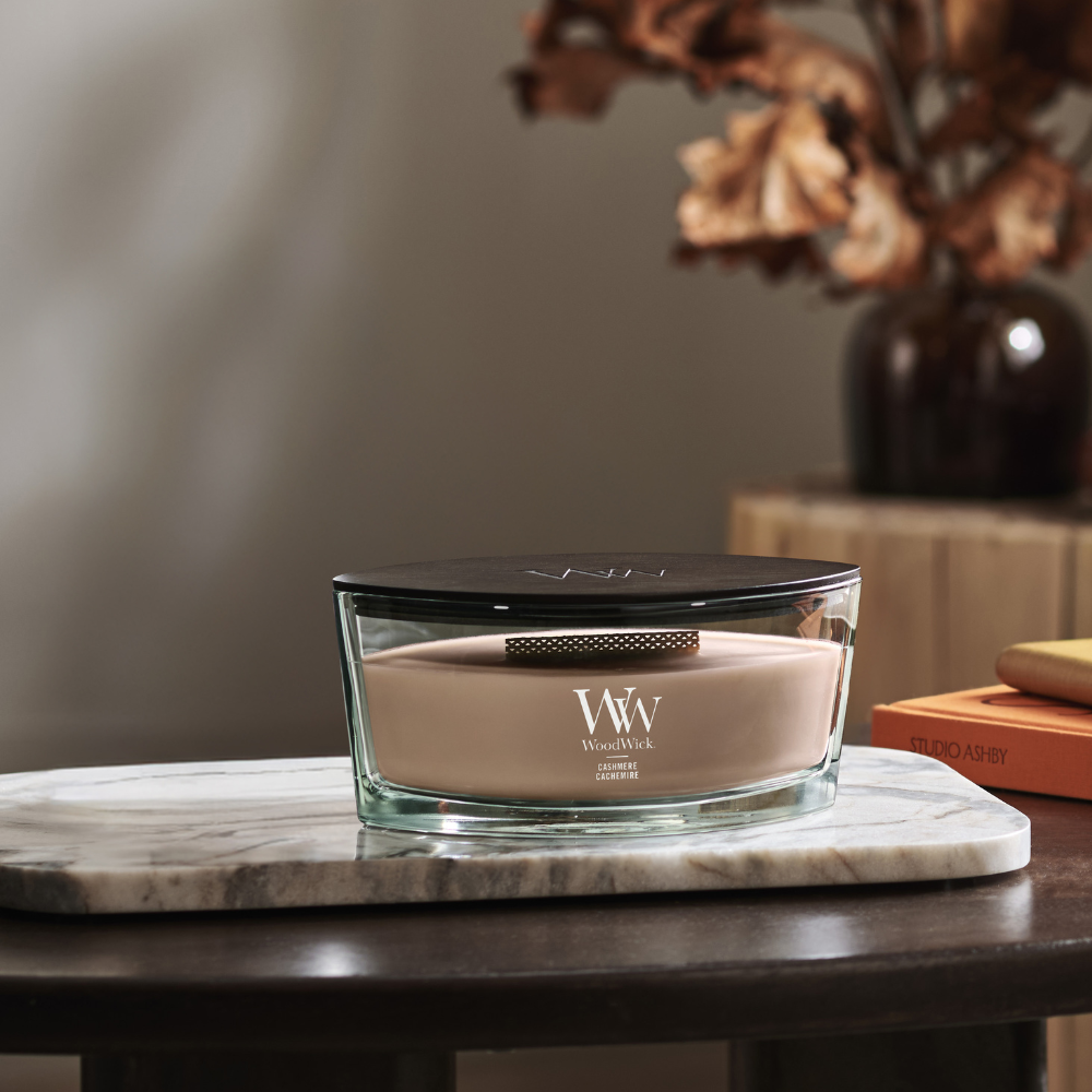 WoodWick Cashmere candle in a clear glass vessel with a wooden lid against decorative background