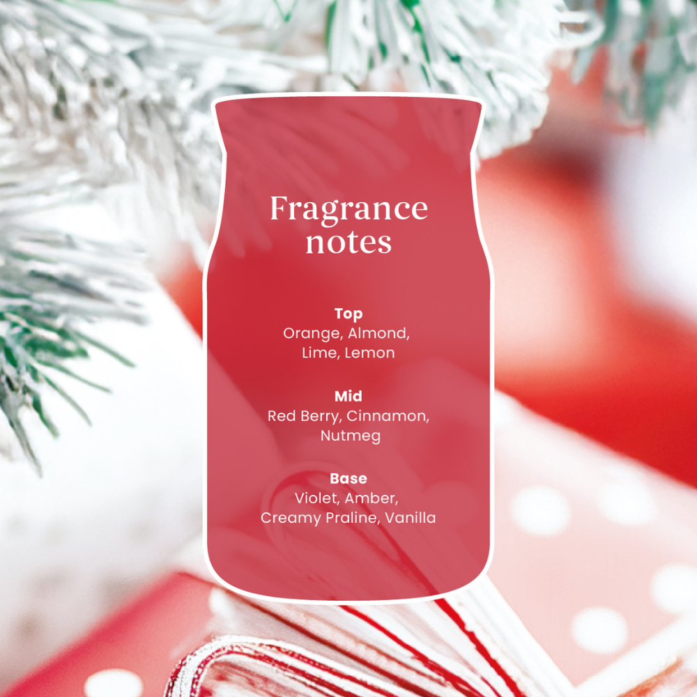Red fragrance bottle with fragrance notes text against a blurred festive background