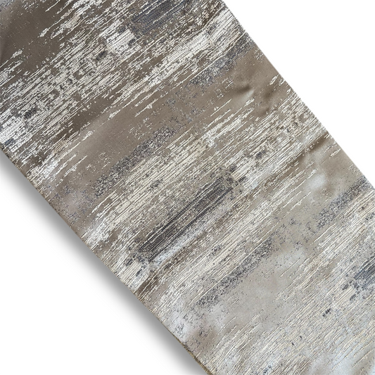 Close-up of Dark Blue Metallic Runner with an abstract brush-stroke pattern, showcasing muted taupe and metallic silver details, laid diagonally on a white background.