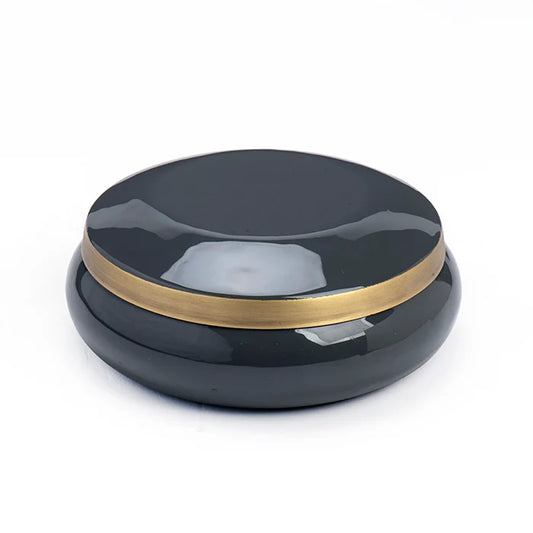 Black round container with gold band on a white background