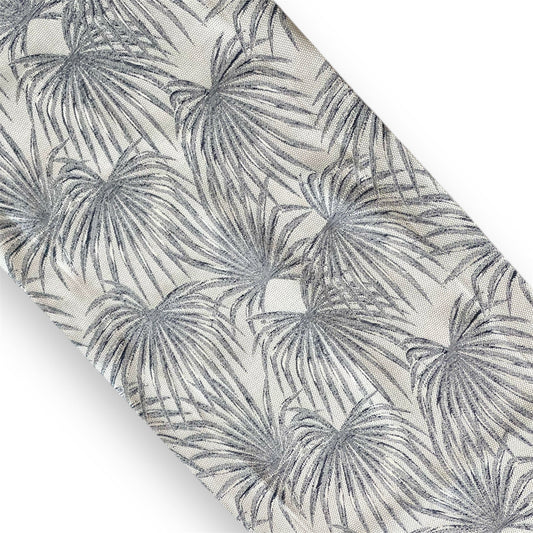 A section of a dark silver-blue area rug with a tropical palm leaf pattern.
