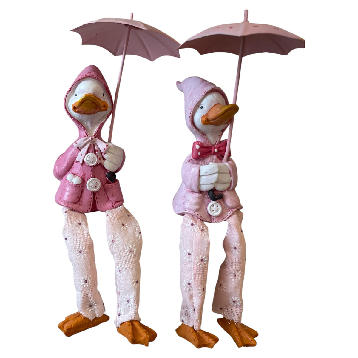 Two decorative ducks in pink outfits holding umbrellas on a white background