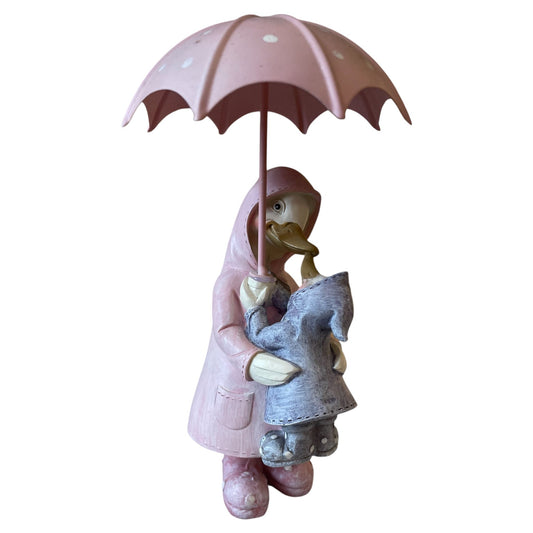 Statue of a child holding a pink umbrella with a duck under a white background
