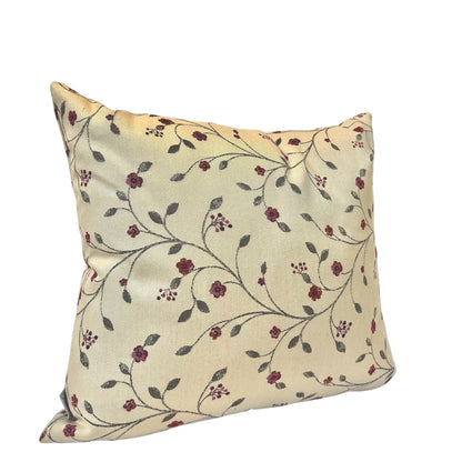 Square cream throw pillow featuring a delicate red and green floral vine pattern against a plain white background.