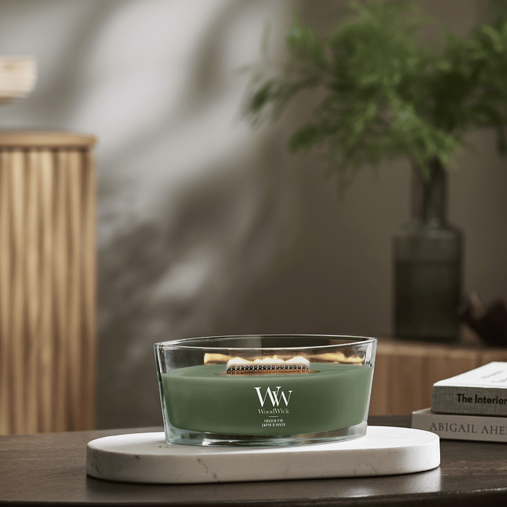 WoodWick Rose Blush ellipse candle in a clear glass jar with an open lid against decorative background
