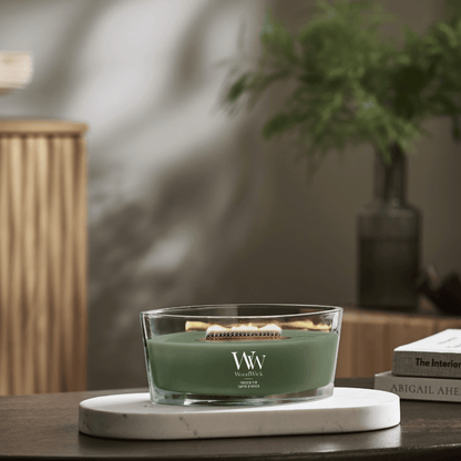 WoodWick Rose Blush ellipse candle in a clear glass jar with an open lid against decorative background