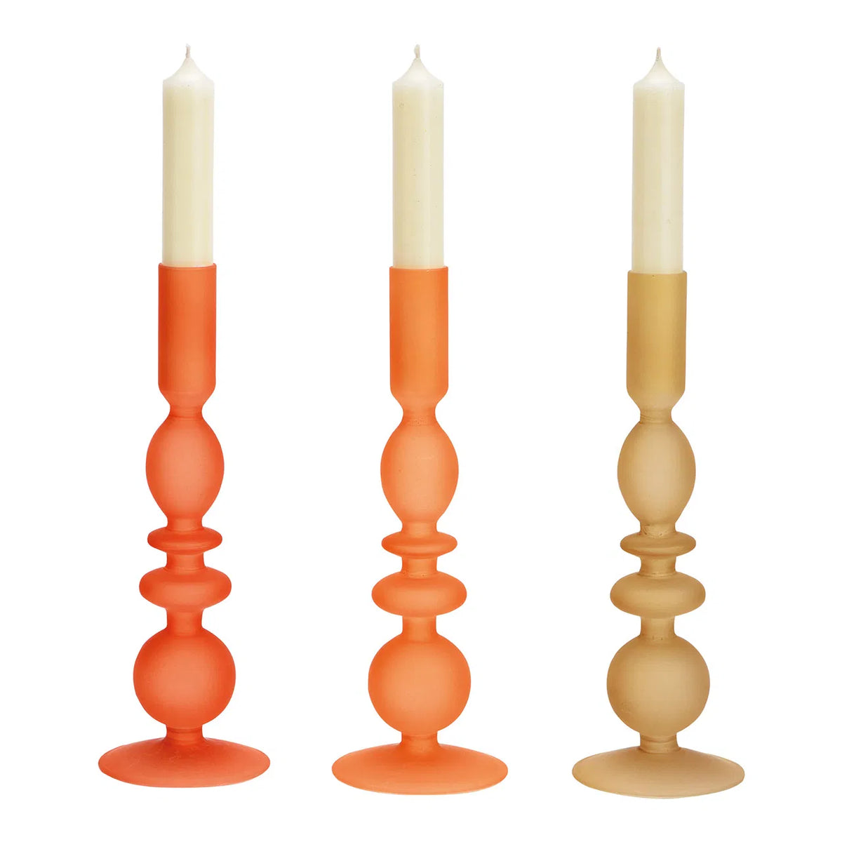 Three glass candle holders in red-orange, orange, and gold-beige colors, each with a candle lit on top.