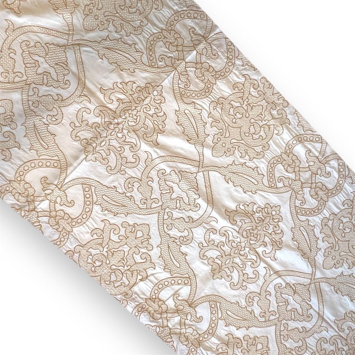 A fabric table runner with a gold pattern on a light background.