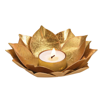 A gold aluminum tealight holder in the shape of a lotus flower with a candle inside.
