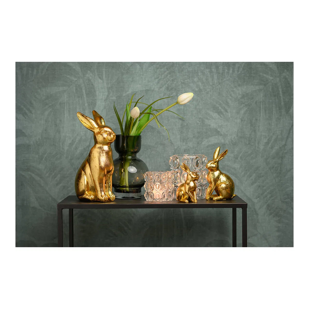 Clear textured glass windlight tealight holders styled on a black table with metallic gold bunny figurines and a dark green glass vase.