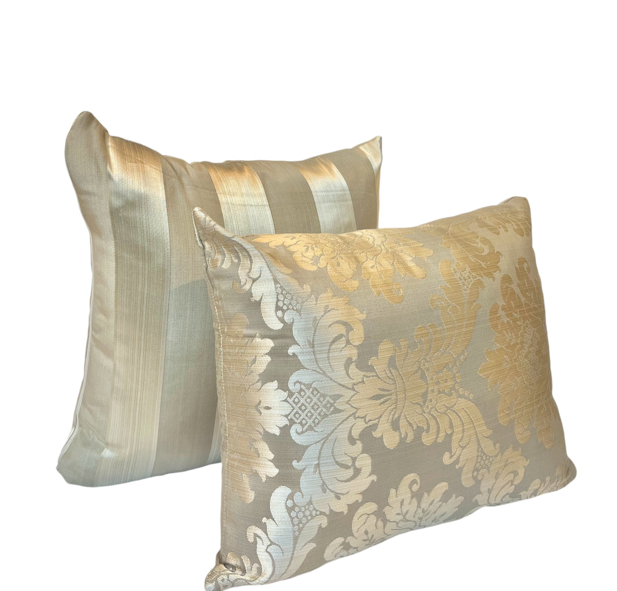 Pair of decorative throw pillows featuring an ornate golden floral damask pattern and soft blue fabric against a white background.