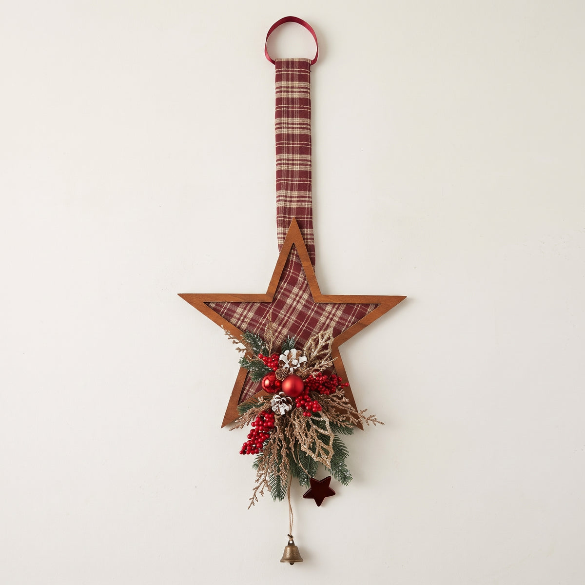 Handcrafted red plaid one-sided star holiday door hanger accented with frosted pine branches, pinecones, berries, and a festive red bow, against a white background