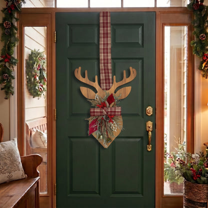 Handcrafted two-sided wooden deer holiday door hanger featuring a festive red plaid tartan ribbon, frosted pine branches, pinecones, berries, and a golden bell, hanging on a classic green front door