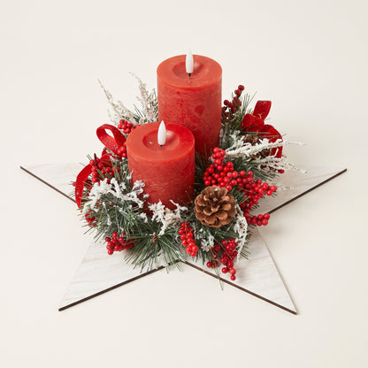 Handmade wooden star Christmas tree centerpiece decorated with frosted pine branches, pinecones, red berries, and two red pillar candles.