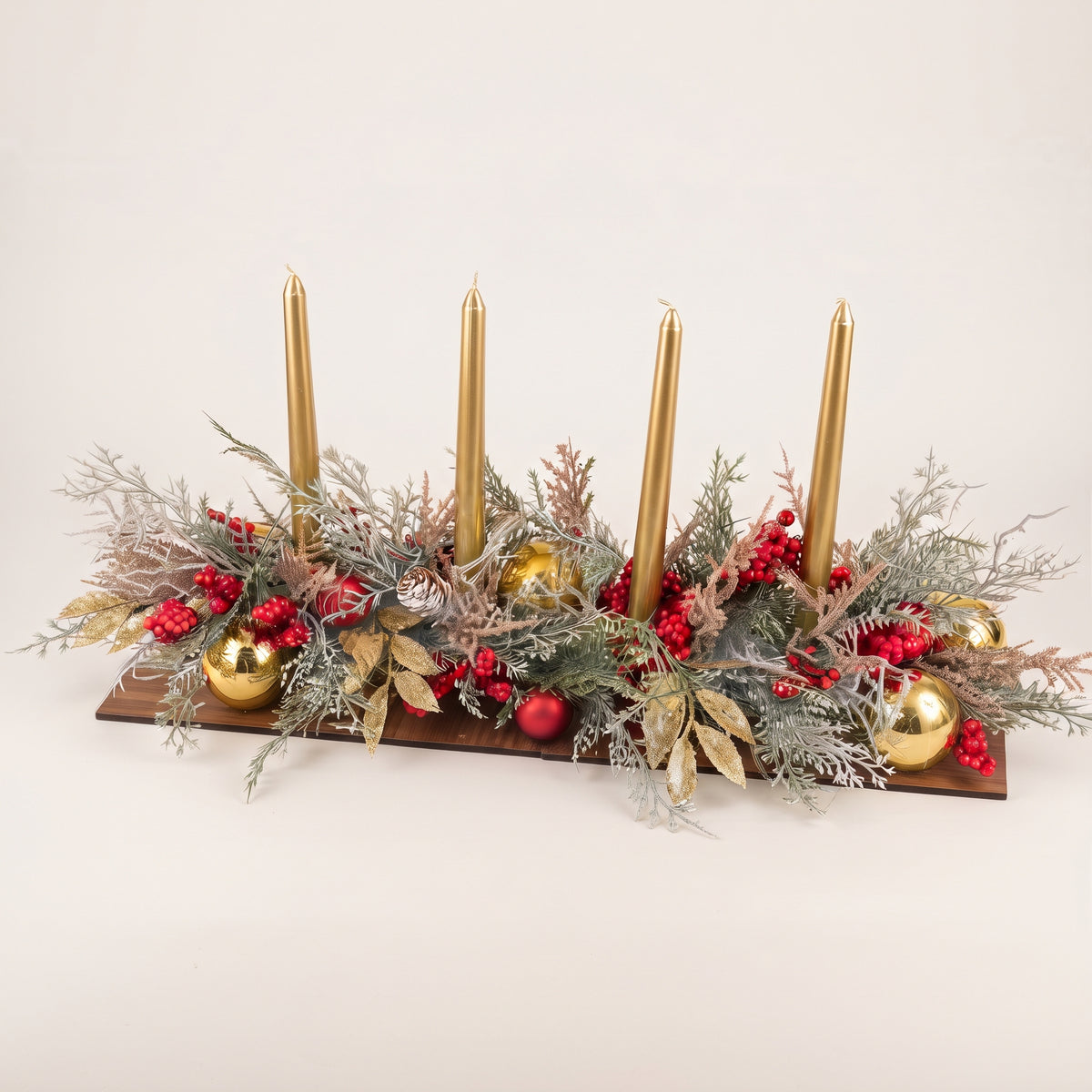 Handmade gold candle centerpiece with festive holiday greenery, red ornaments, and tall gold taper candles, against white background.