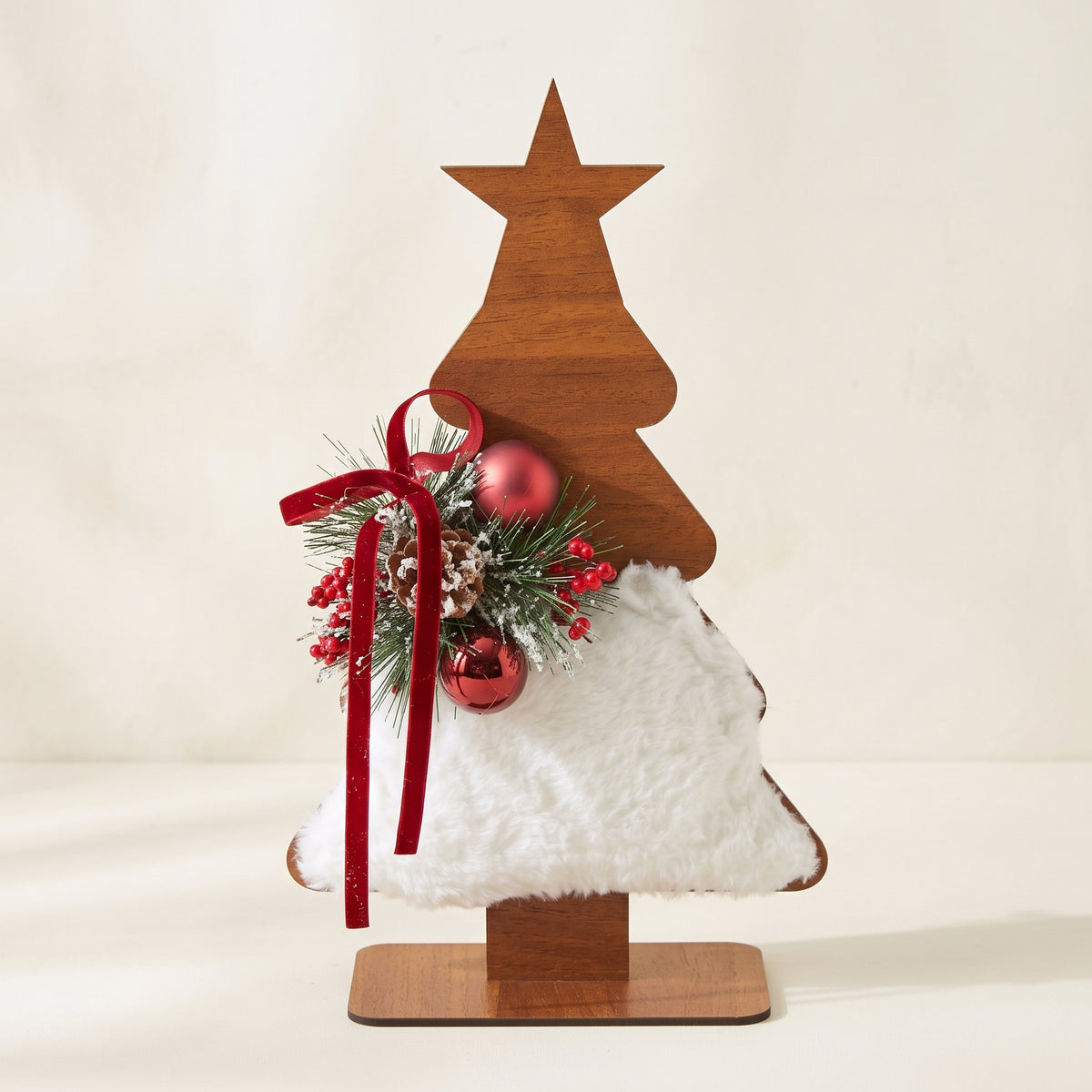 Handmade wooden star Christmas tree centerpiece decorated with pine branches, pinecones, and a white-red holiday ornament.