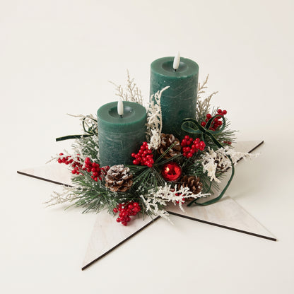 Handmade green pillar candle centerpiece on a white wooden star with pinecones and berries