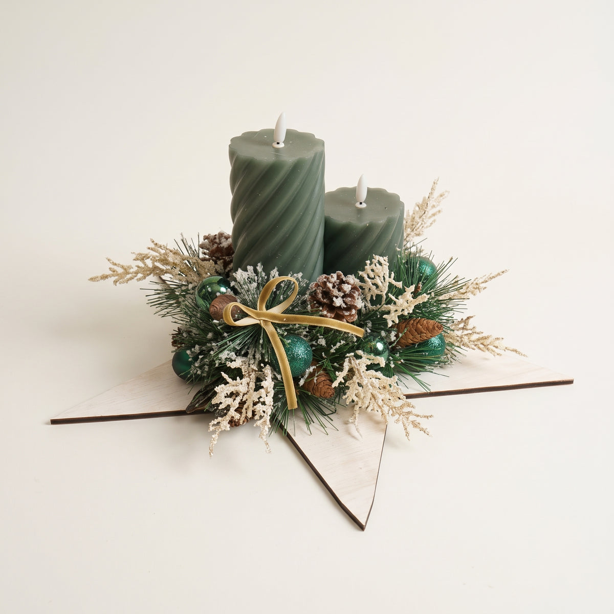 Handcrafted wooden white star candle centerpiece featuring green pillar candles, natural pinecones, and berries, against white background
