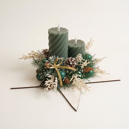 Handcrafted wooden white star candle centerpiece featuring green pillar candles, natural pinecones, and berries, against white background