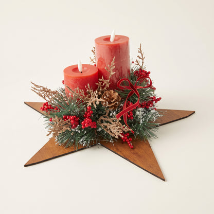 Handcrafted red pillar candle centerpiece featuring natural pinecones and green foliage on a wooden star base