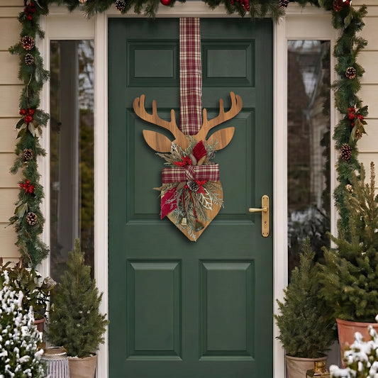 Handcrafted two-sided wooden deer holiday door hanger featuring a festive red plaid tartan ribbon, frosted pine branches, pinecones, berries, and a golden bell, hanging on a classic green front door