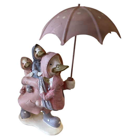 Statue of two ducks in pink raincoats with an umbrella on a white background