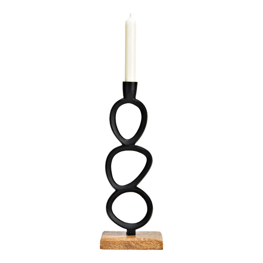 A black metal candlestick with a circular design, standing on a wooden base, with a white candle placed on top.