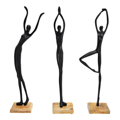 Three black metal stand figures in different poses of dancing, set on wooden bases.