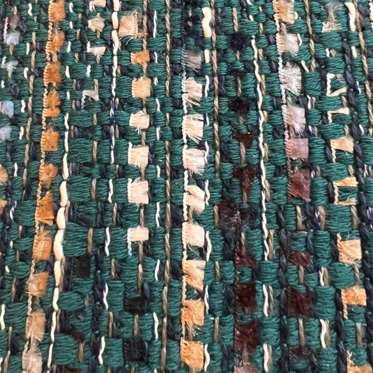 Extreme close-up detail of a rich, multi-colored tweed weave featuring woven threads of ocean teal, emerald green, navy blue, and subtle metallic silver.