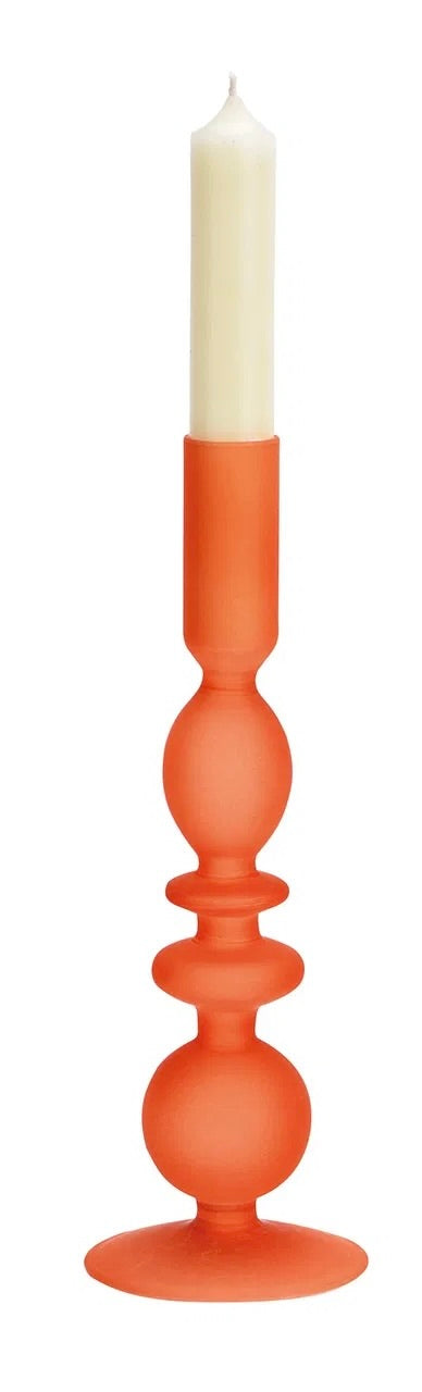 Orange glass candle holder, with a white candle on top.