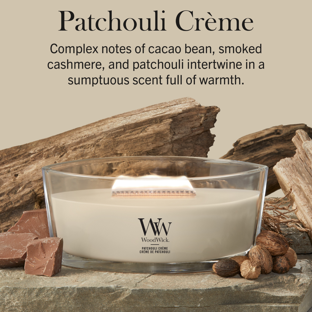 WoodWick Patchouli Crème candle in a clear glass jar with a wooden lid against a neutral beige background with cocoa beans and wood accents.
