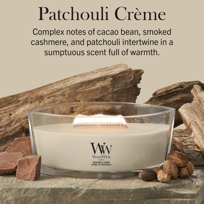 WoodWick Patchouli Crème candle in a clear glass jar with a wooden lid against a neutral beige background with cocoa beans and wood accents.