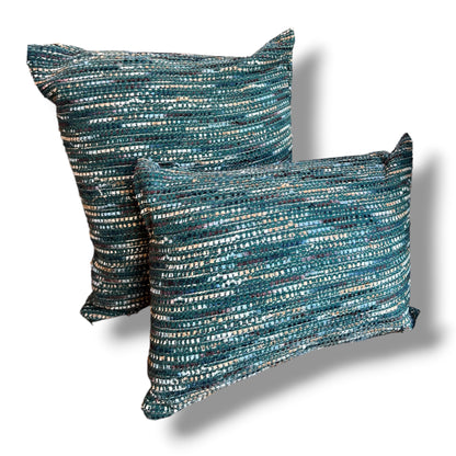 Set of two textured tweed decorative pillows, featuring a rectangular lumbar pillow in front of a matching square cushion in woven ocean teal, emerald green, navy, and metallic silver threads against a plain white background.