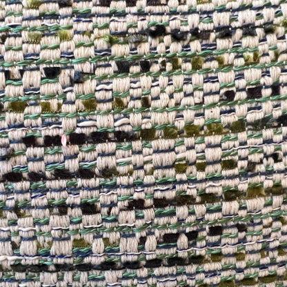 Extreme close-up detail of a textured tweed fabric weave, featuring interconnected threads of sage green, cream, navy blue, and olive green.