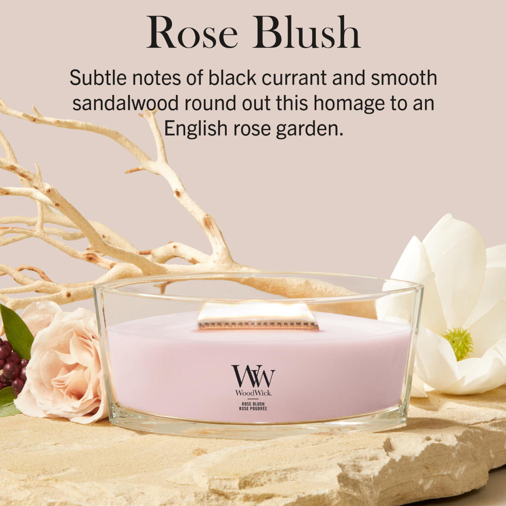 Rose Blush candle in a clear glass jar with a wooden wick set on a stone tray next to a white flower and soft pink background text.