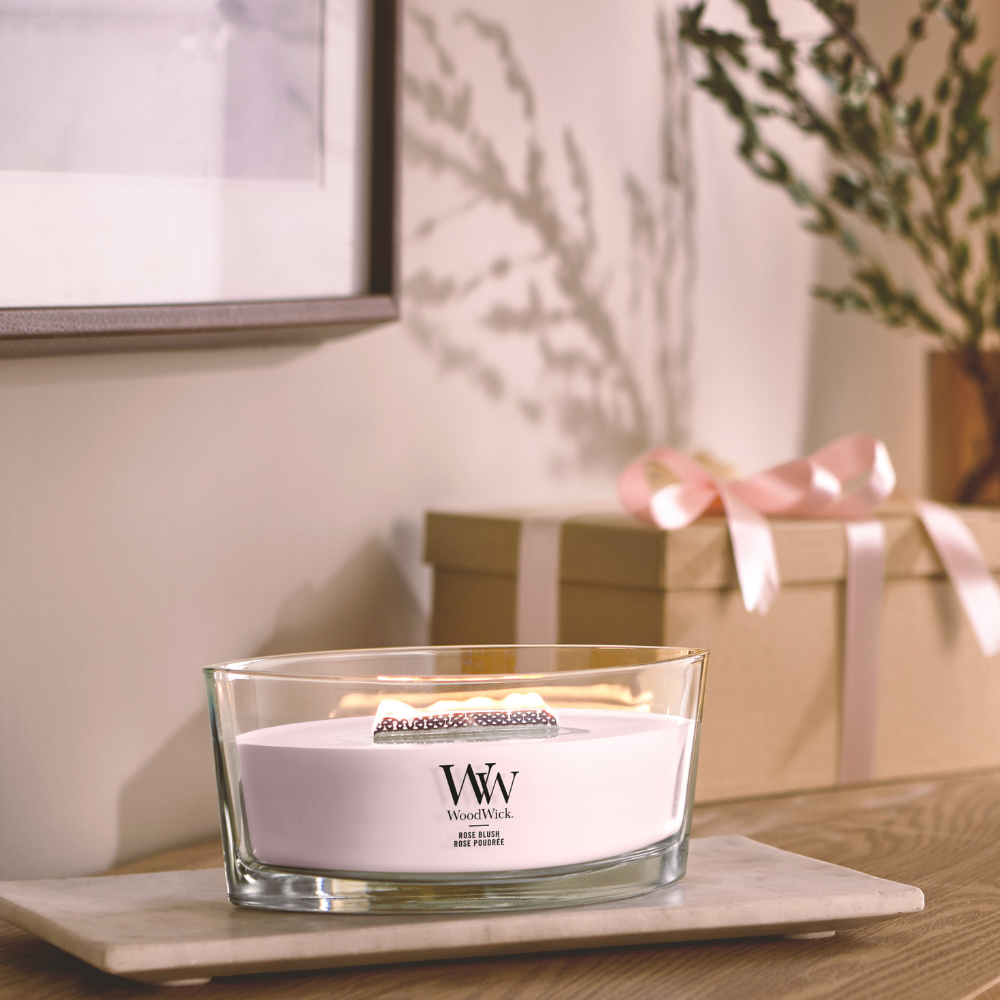 Rose Blush candle in a clear glass jar with an open lid against decorative backround