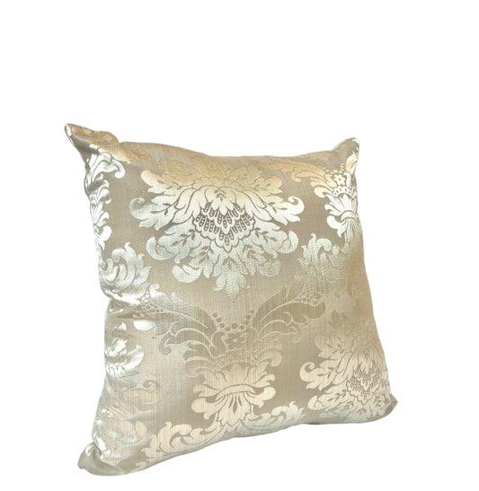 A square-shaped throw pillow with a gold and beige floral pattern.