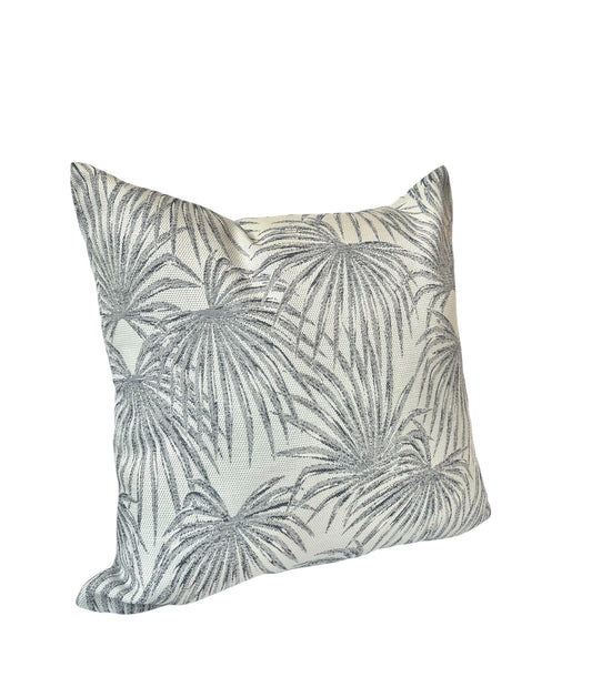 A square throw pillow with a tropical palm leaf pattern in shades of blue and gray.