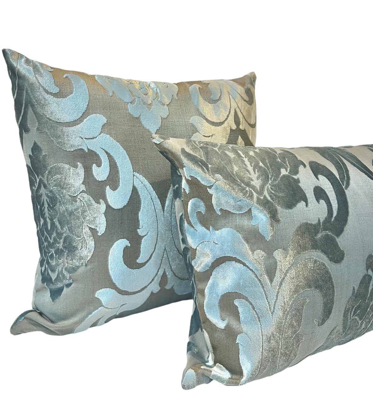Pair of square throw pillows featuring a shimmering light blue and silver floral damask pattern on a white background.