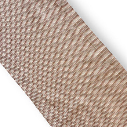 Close-up view of a textured woven linen table runner in a neutral taupe beige shade against a white background.