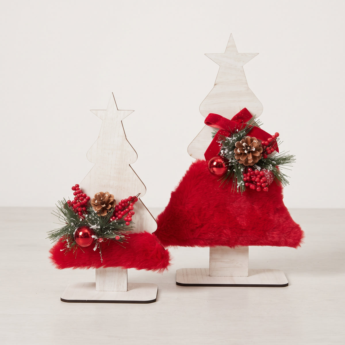 Two handmades wooden star Christmas tree centerpiece decorated with pine branches, pinecones, and a red holiday ornament.