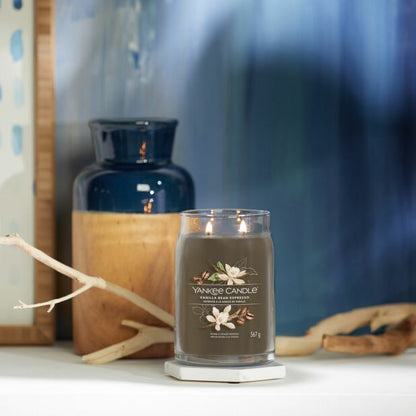 A Yankee Candle vanilla bean espresso candle in a clear glass jar with a brown label, showing the candle's weight of 550 grams.